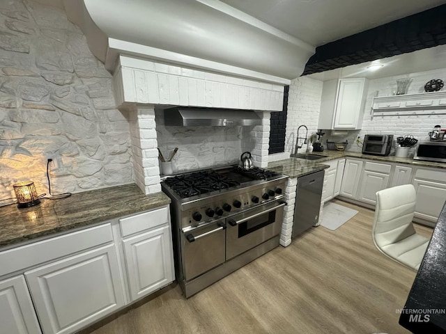 kitchen featuring sink, wall chimney range hood, stainless steel appliances, white cabinets, and light wood-type flooring