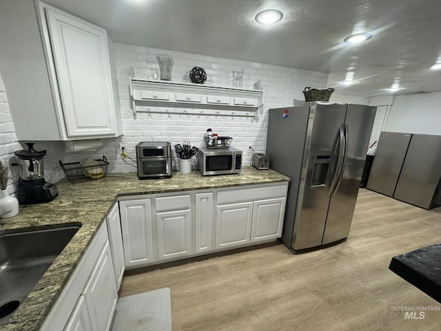 kitchen featuring appliances with stainless steel finishes, white cabinets, light stone counters, and light hardwood / wood-style flooring