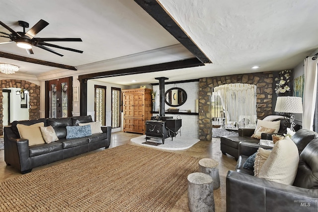 living room with beamed ceiling, a wood stove, ceiling fan, a raised ceiling, and a textured ceiling