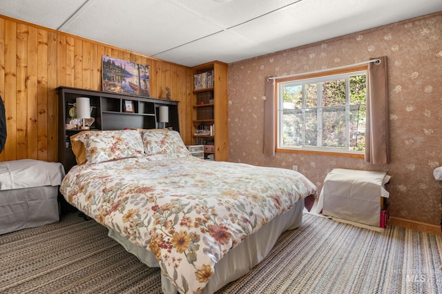 bedroom featuring carpet flooring, wallpapered walls, and wood walls