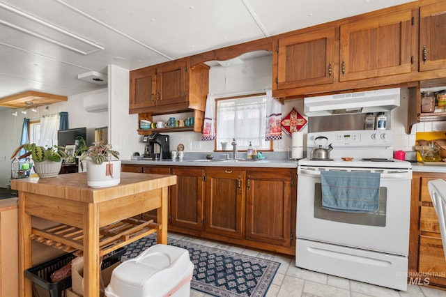 kitchen featuring white electric range oven, under cabinet range hood, a sink, light countertops, and brown cabinets