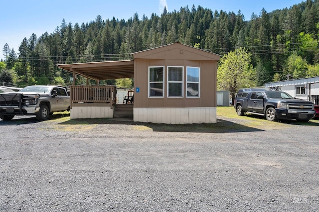 view of front of house featuring a view of trees and a deck