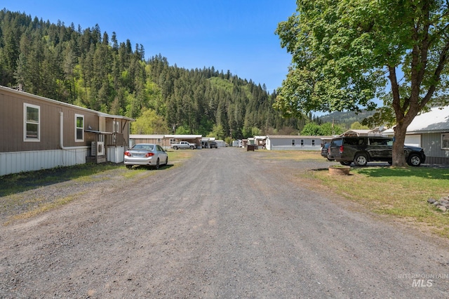 view of dirt / gravel road featuring a view of trees