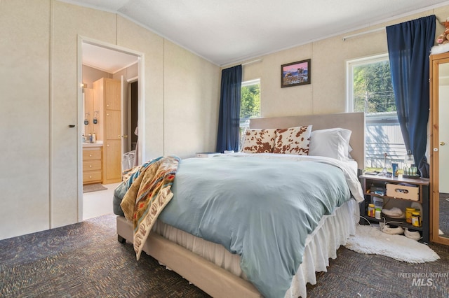 bedroom with lofted ceiling, crown molding, and connected bathroom