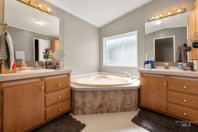 full bath featuring two vanities, vaulted ceiling, a garden tub, and ornamental molding