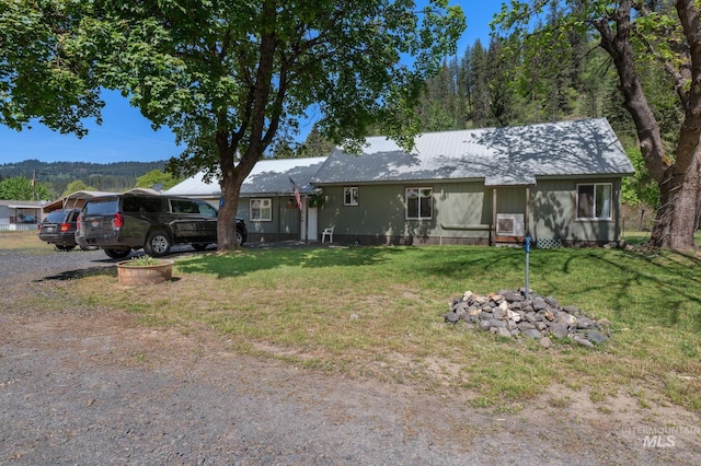 ranch-style home featuring metal roof and a front lawn