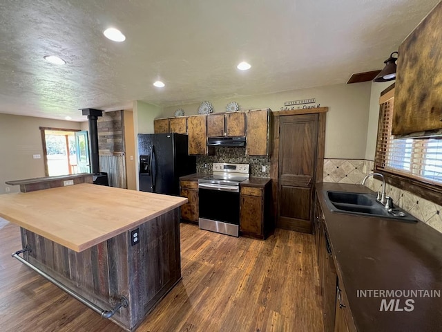 13974 Rustic Rd, Mccall, ID 83638 - kitchen with stainless steel electric stove, under cabinet range hood, black fridge, a sink, and a wood stove