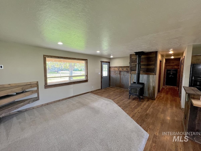 13974 Rustic Rd, Mccall, ID 83638 - unfurnished living room featuring a wood stove, a textured ceiling, wood finished floors, recessed lighting, and baseboards