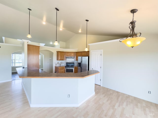 166 Eric Rd, Shoshone, ID 83352 - kitchen featuring stainless steel appliances, arched walkways, brown cabinetry, light wood-style floors, and vaulted ceiling