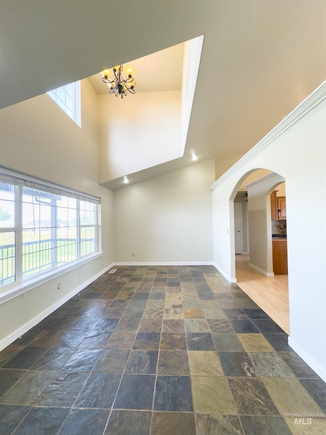 166 Eric Rd, Shoshone, ID 83352 - unfurnished living room with stone tile floors, a chandelier, baseboards, plenty of natural light, and a high ceiling
