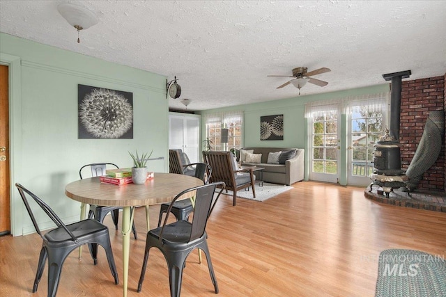 6426 W Fairfield Ave, Boise, ID 83709 - dining space featuring a wood stove, a ceiling fan, light wood-style floors, and a textured ceiling