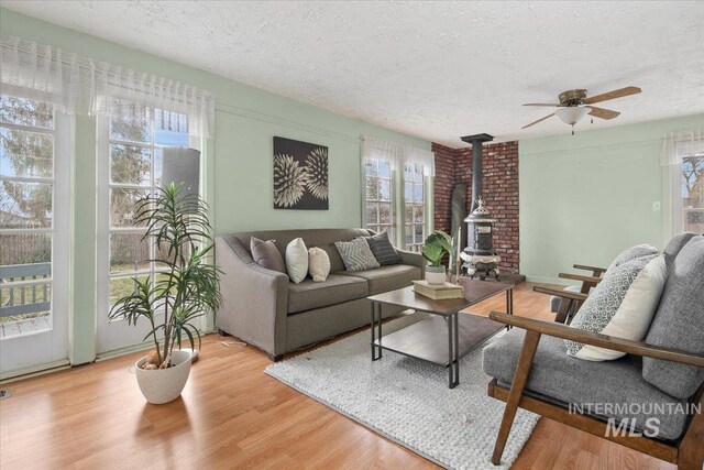 6426 W Fairfield Ave, Boise, ID 83709 - living room featuring a wood stove, a textured ceiling, a ceiling fan, healthy amount of natural light, and wood finished floors