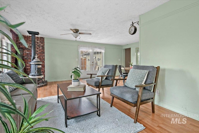 6426 W Fairfield Ave, Boise, ID 83709 - living area featuring a wood stove, a ceiling fan, wood finished floors, a textured ceiling, and baseboards