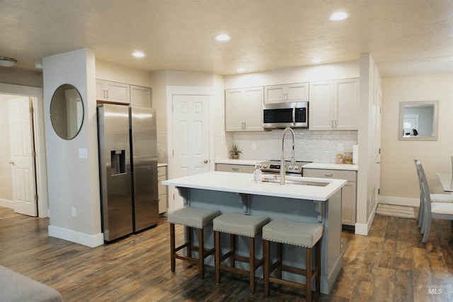 kitchen with tasteful backsplash, appliances with stainless steel finishes, dark hardwood / wood-style floors, and white cabinets