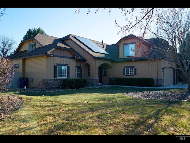 view of front facade featuring a garage, a front lawn, and solar panels