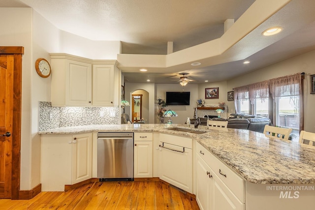 kitchen with tasteful backsplash, dishwasher, sink, light stone countertops, and light hardwood / wood-style flooring