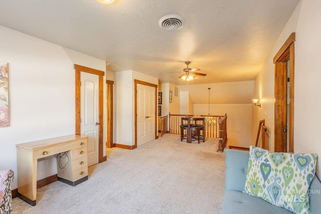 living room featuring light carpet, ceiling fan, and a textured ceiling