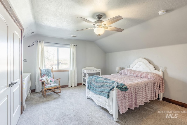 carpeted bedroom featuring ceiling fan, lofted ceiling, and a textured ceiling