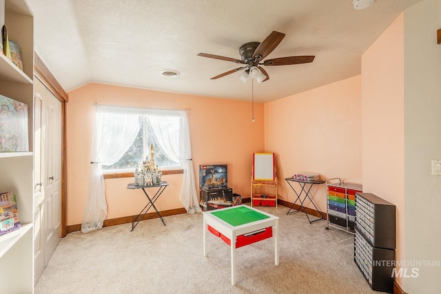 recreation room with lofted ceiling, ceiling fan, light colored carpet, and a textured ceiling