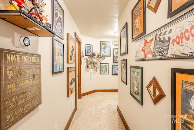 corridor with light carpet and a textured ceiling