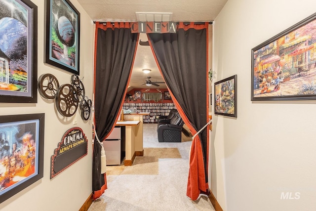 hall with light colored carpet and a textured ceiling