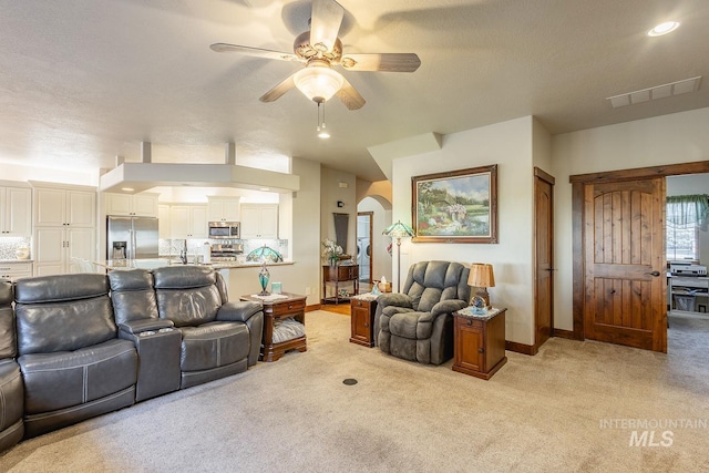 living room with ceiling fan, light colored carpet, and a textured ceiling