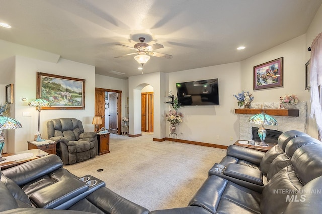 carpeted living room featuring ceiling fan and a fireplace