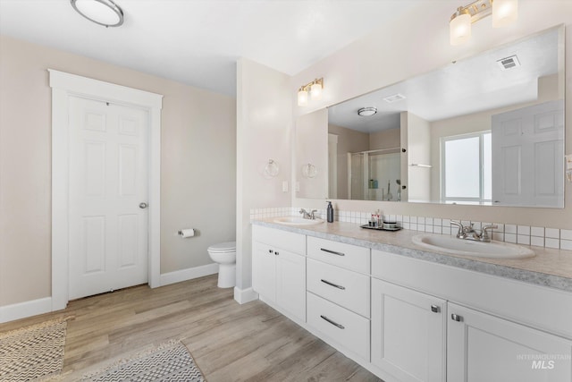 12817 Ironstone Dr, Nampa, ID 83651 - full bath featuring double vanity, toilet, baseboards, a shower with door, and wood finished floors