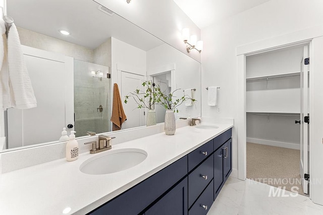 full bath featuring a shower stall, marble finish flooring, double vanity, and a walk in closet