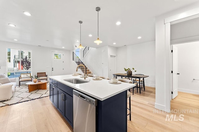kitchen with dishwasher, a sink, light wood-style flooring, open floor plan, and light countertops