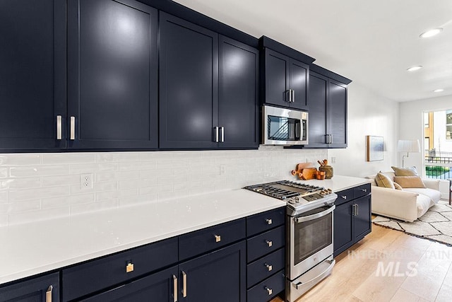 kitchen featuring appliances with stainless steel finishes, open floor plan, backsplash, recessed lighting, and light wood-style flooring