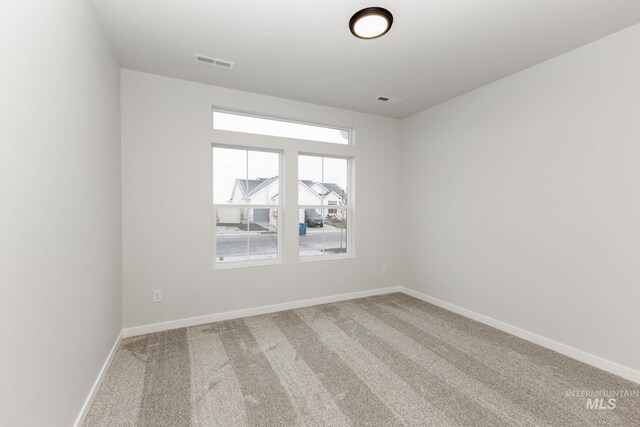 spare room with visible vents, carpet floors, and baseboards