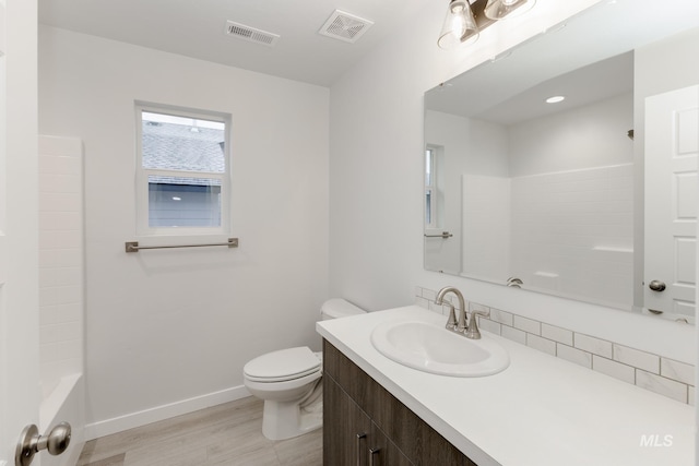 bathroom featuring baseboards, visible vents, wood finished floors, and toilet