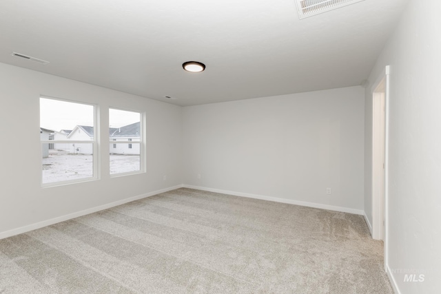 empty room featuring baseboards, visible vents, and light colored carpet