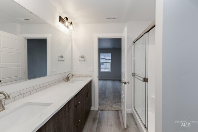 bathroom with a sink, a shower stall, wood finished floors, and visible vents