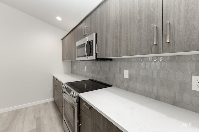 kitchen with light wood-type flooring, modern cabinets, appliances with stainless steel finishes, and light countertops