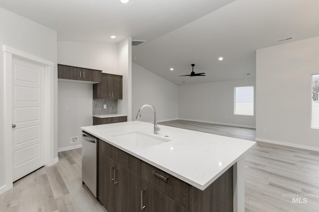 kitchen featuring light wood finished floors, dishwasher, a sink, and light countertops