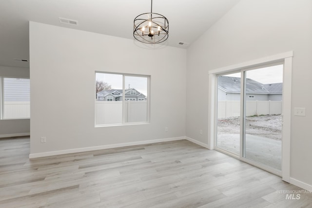 unfurnished dining area with an inviting chandelier, visible vents, light wood-style flooring, and baseboards