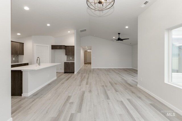 unfurnished living room featuring baseboards, visible vents, light wood-style floors, and vaulted ceiling