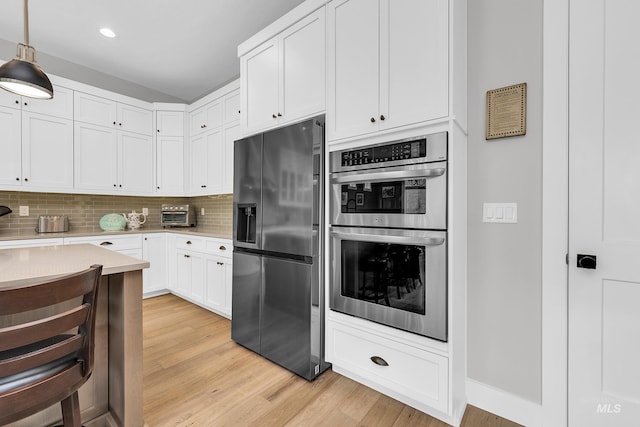 kitchen with light wood-style flooring, decorative backsplash, stainless steel appliances, light countertops, and white cabinets