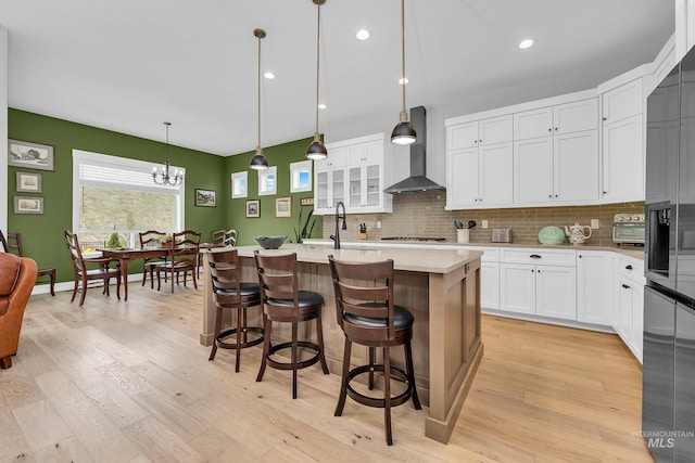 kitchen featuring stainless steel gas cooktop, backsplash, wall chimney range hood, and light countertops