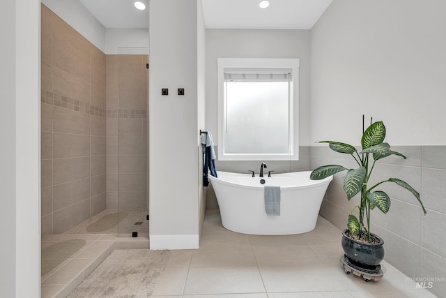 bathroom with recessed lighting, a freestanding bath, a shower stall, and tile patterned flooring