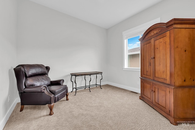 sitting room with baseboards and light carpet