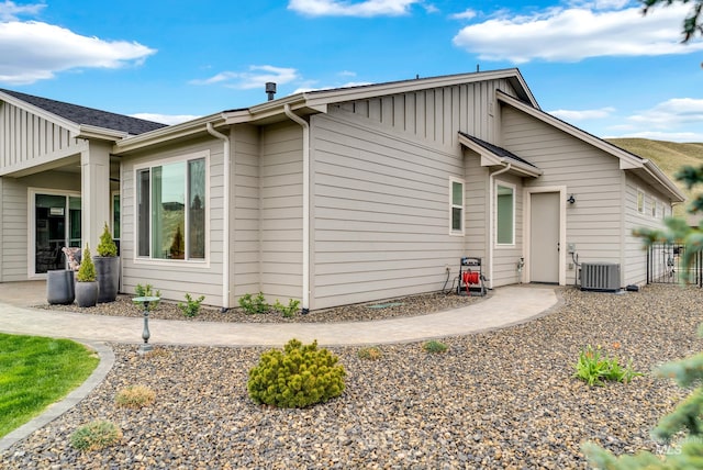 view of property exterior with fence, board and batten siding, and central air condition unit