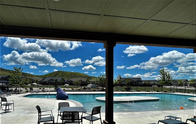 community pool with a residential view, a mountain view, a patio area, and fence