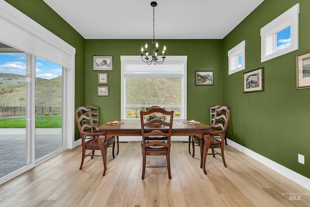 dining room with baseboards, an inviting chandelier, and light wood-style floors