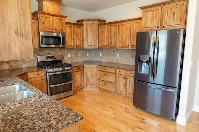 6023 S Augustine Ave, Boise, ID 83709 - kitchen with appliances with stainless steel finishes, light wood-style flooring, a sink, brown cabinetry, and backsplash