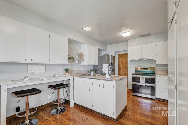 833 Nebraska, Gooding, ID 83330 - kitchen with stainless steel appliances, a peninsula, white cabinetry, light countertops, and wood finished floors