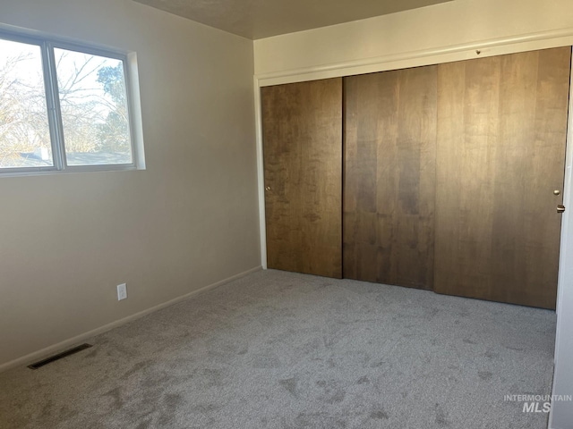 unfurnished bedroom with a closet and light colored carpet