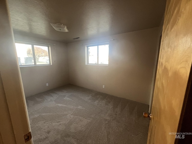 unfurnished room featuring carpet flooring and a textured ceiling